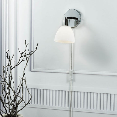 Ray wall light chrome on a wall, elegant design with chrome-colored bracket and glass lampshade.