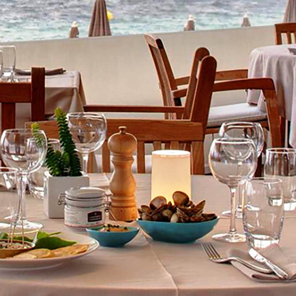 Elegantes gedeckter Tisch im Restaurant am Meer mit Tischlampen, Gläsern und Dekoration.