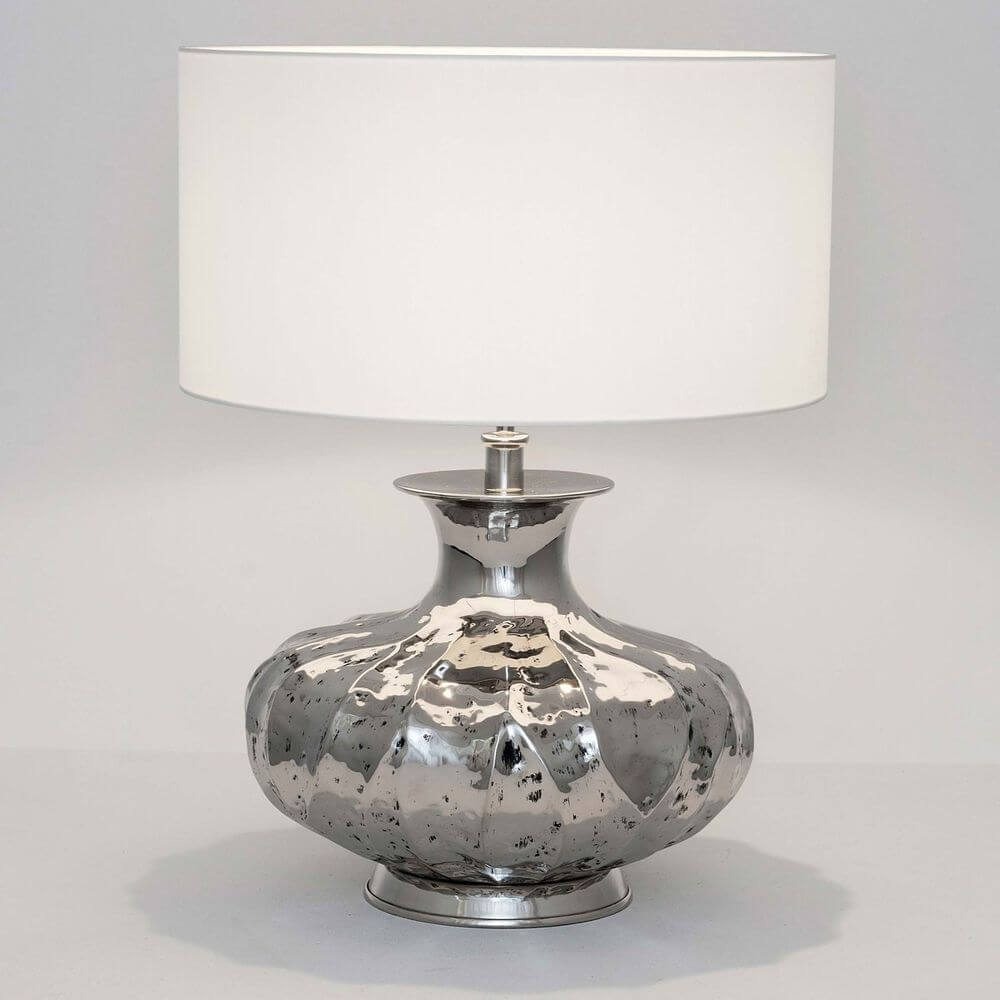 Lampe de table Damasco en aluminium nickelé argenté sur fond clair avec une forme simple.