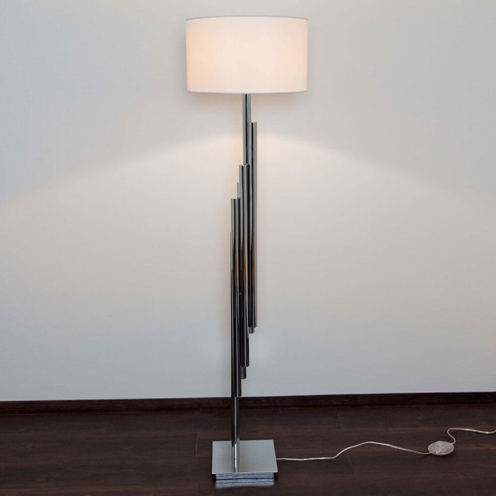 Stehleuchte Trimestre Metall verchromt Silber mit modernem Design und weißem Lampenschirm auf dunklem Boden.