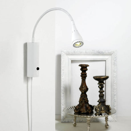 Applique murale Mento LED blanc montée sur un mur à côté de chandeliers et d’un cadre photo.