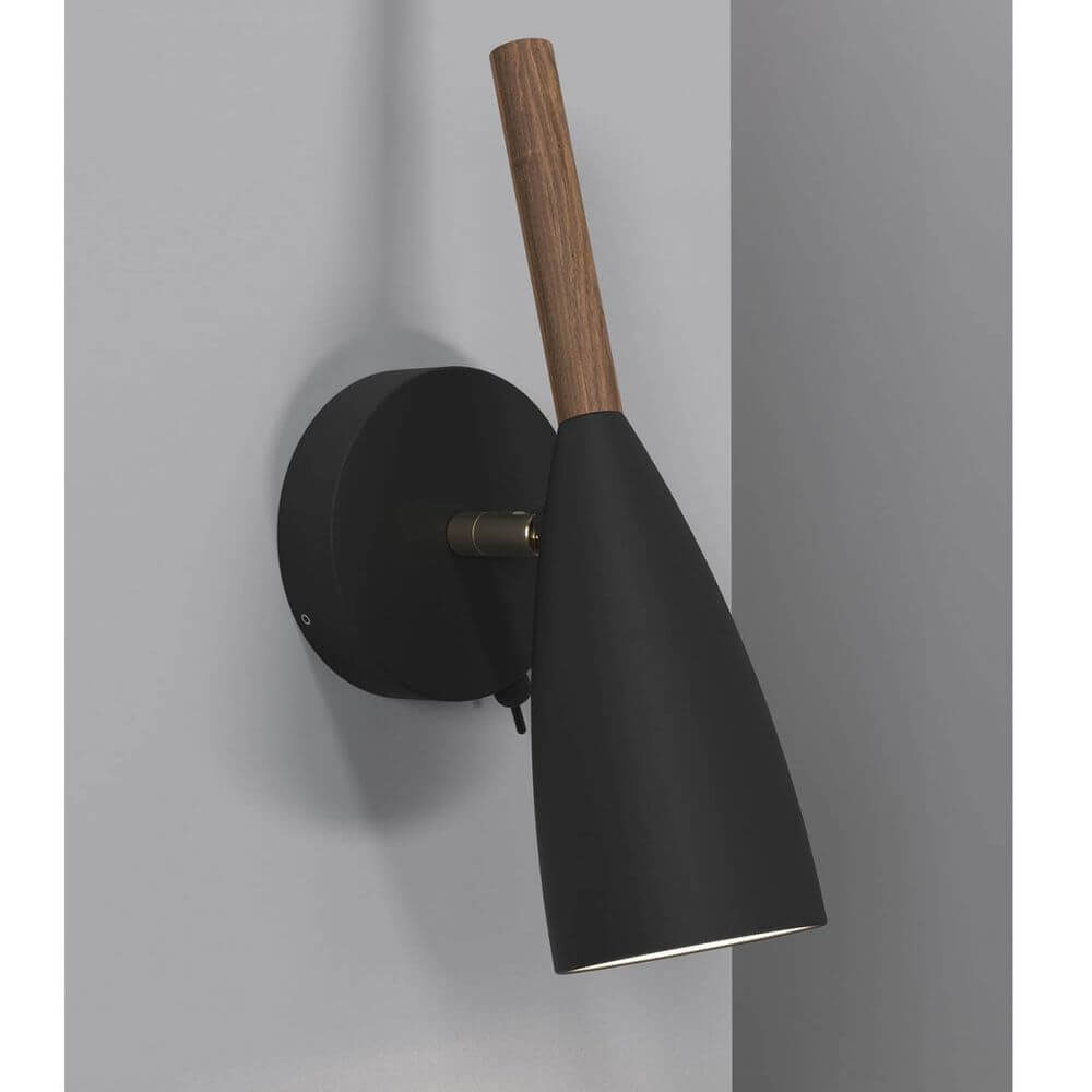 Pure Wandleuchte Schwarz mit geöltem Nussbaum und elegantem Design an einer grauen Wand.