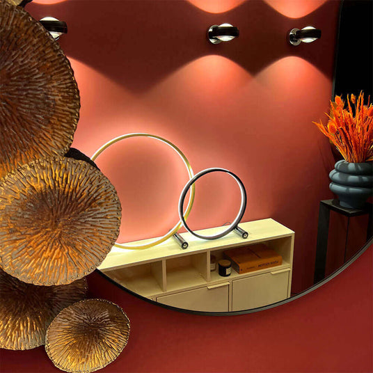 Elegante Wandspiegel mit runden Lichtakzenten und Dekor aus Metall und Pflanzen im modernen Raumdesign.