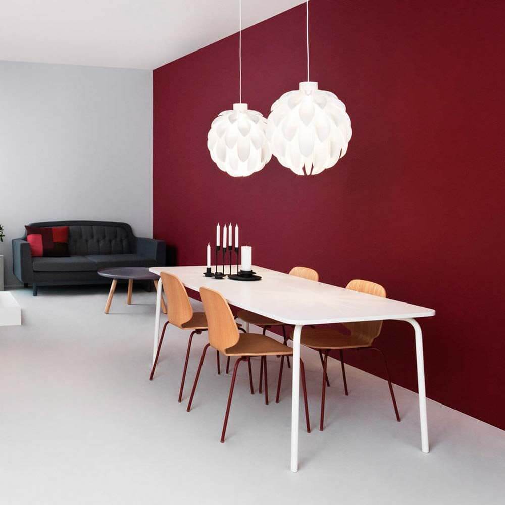 Abgerundete Pendelleuchte Norm12 XL Weiß im modernen Essbereich mit roter Wand und minimalistischen Möbeln.