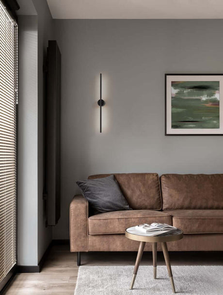 Aden LED Væglampe 3000K Sort på grå væg over brun sofa, slankt mat aluminium design, 90 cm minimalistisk væglampe