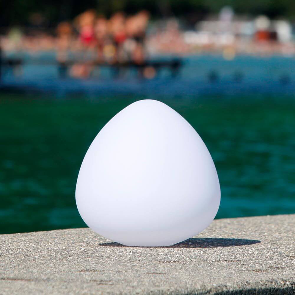 Akku LED-Außenlampe Stone XL in runder Form am Wasser, ideal für Garten und Terrasse.