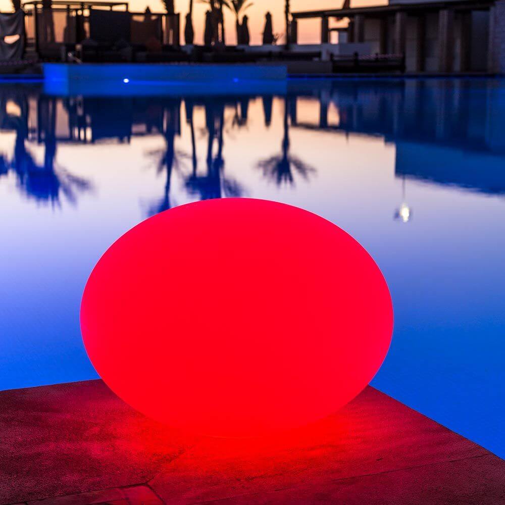 Akku LED-Designleuchte Flatball in Rot am Pool bei Sonnenuntergang, ideal für Garten und Terrasse.