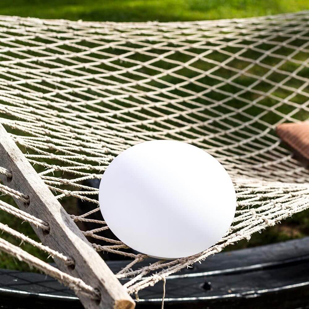 Akku LED-Designleuchte Flatball auf einer Hängematte, ideal für Garten und Terrasse, mit bruchfestem und schwimmfähigem Design.