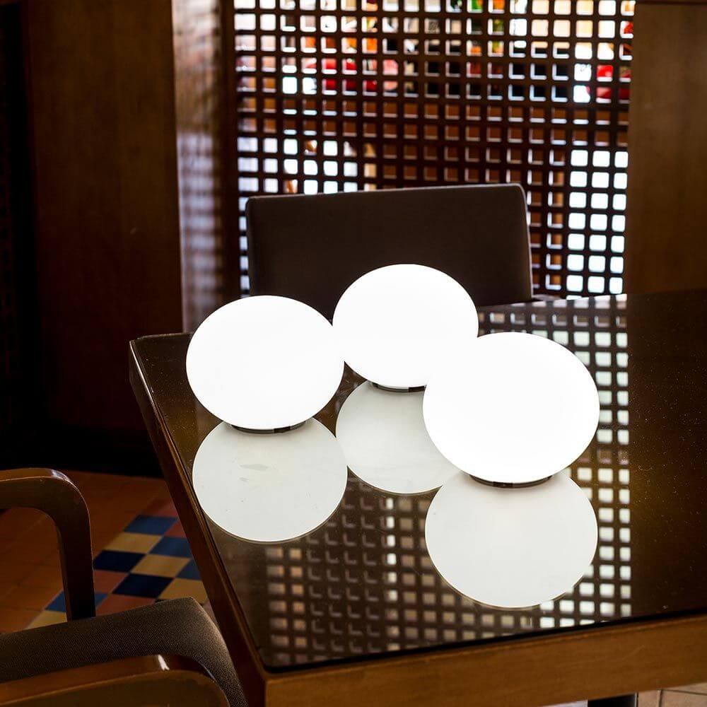 Drei leuchtende Akku LED-Designleuchten Flatball auf einem Tisch, ideal für Garten und Terrasse.