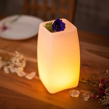 Lámpara de mesa inalámbrica LED Stele con control por app sobre una mesa con flores