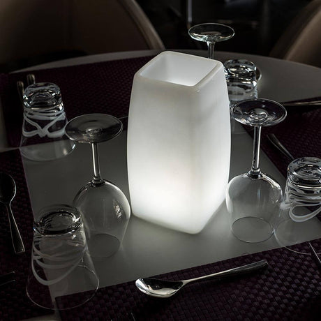 Lámpara de mesa inalámbrica LED Stele con control por app sobre una mesa con vasos y cubiertos, iluminación atmosférica.