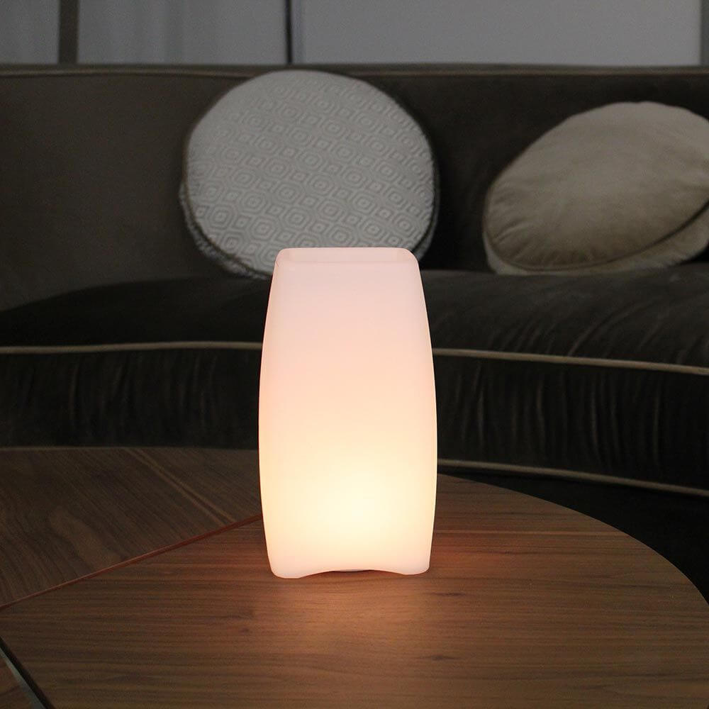 Akku LED-Tischlampe Stele mit App-Steuerung auf einem Tisch im gemütlichen Wohnbereich.