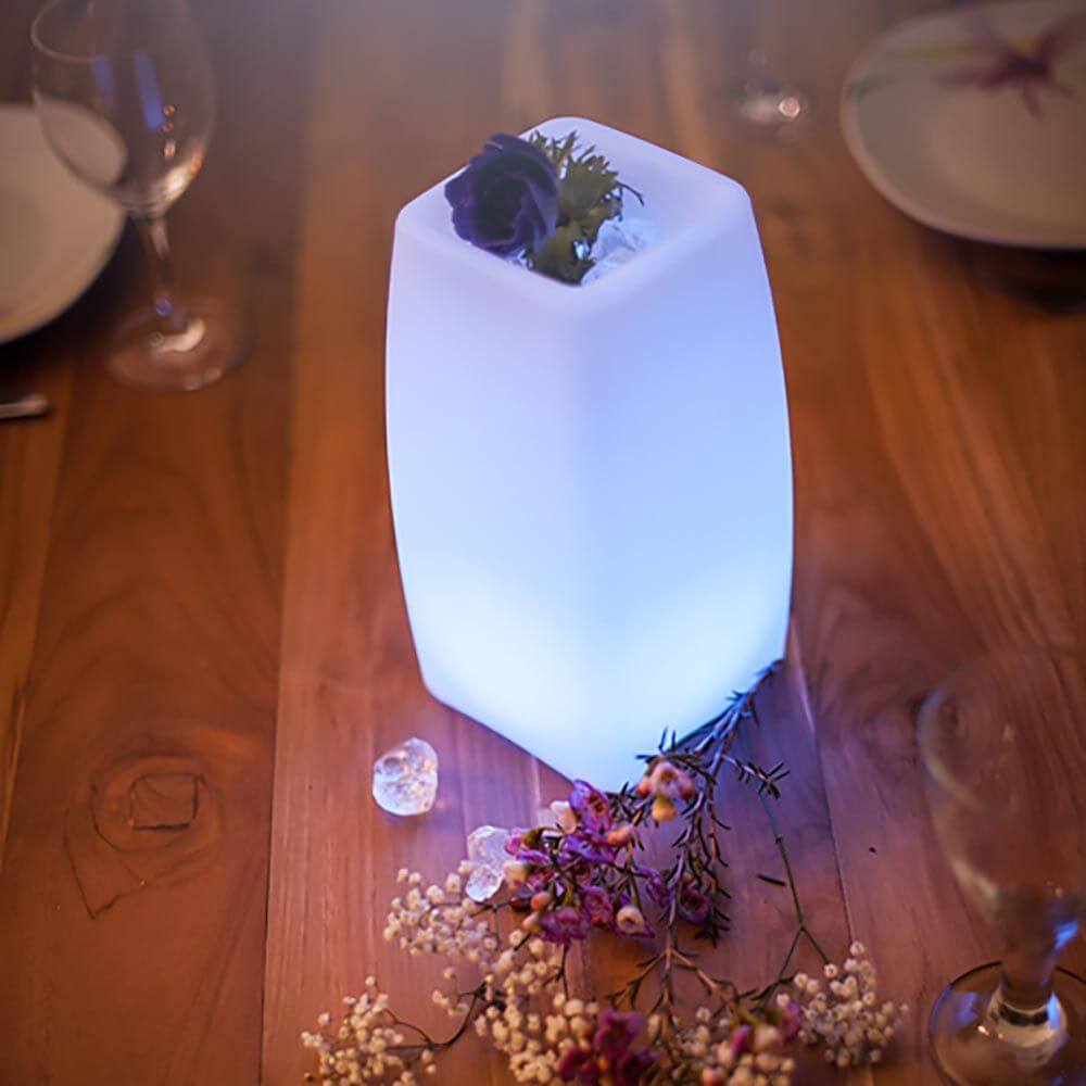 Akku LED-Tischlampe Stele mit App-Steuerung beleuchtet einen Tisch, dekoriert mit Blüten und Glaskugeln.