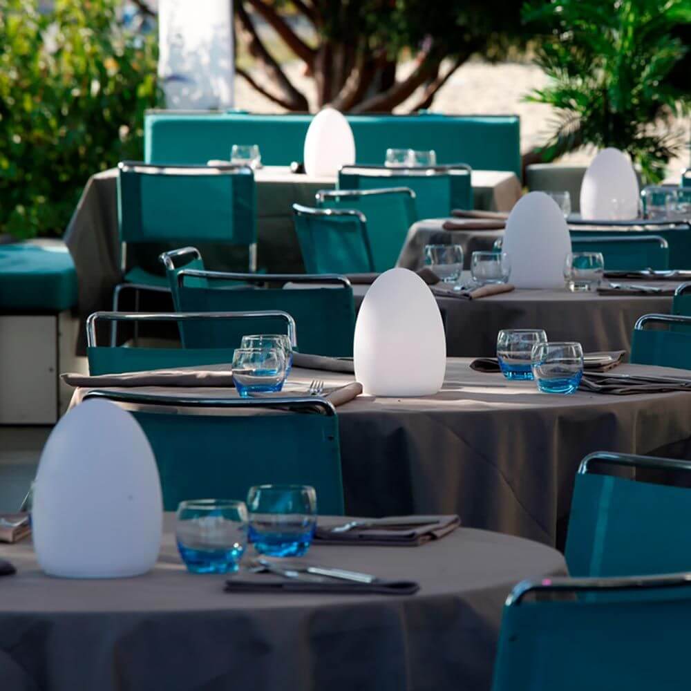 Lampada da tavolo LED Egg con batteria e controllo tramite app su un elegante tavolo in un ristorante moderno.