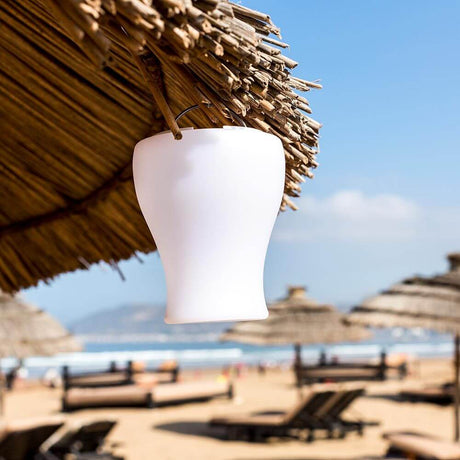 Vaso da tavolo a batteria LED Olio con controllo tramite app appeso sotto un ombrellone sulla spiaggia.