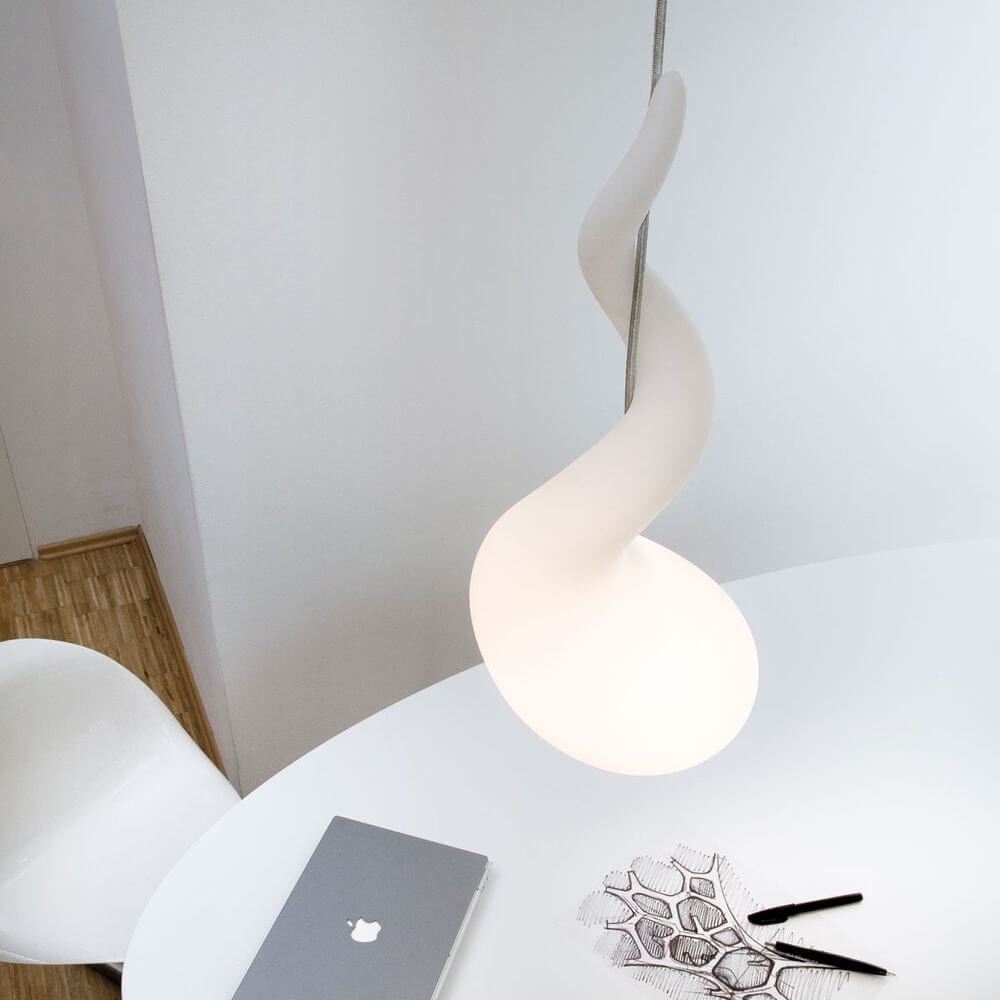 Alien M Pendelleuchte 65cm Liquid-Light Weiß an einem modernen Tisch mit Laptop und Notizblock.