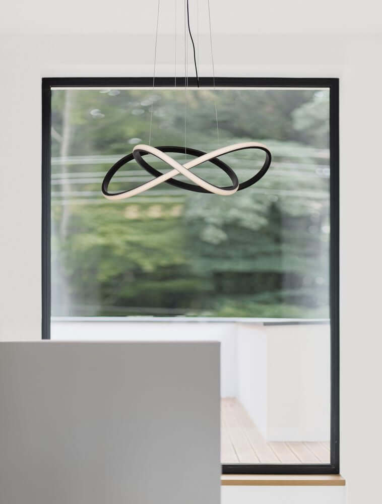 Amara LED Pendelleuchte Ø 56cm schwebt über einem Tisch mit modernem Design und großen Fenstern im Hintergrund.
