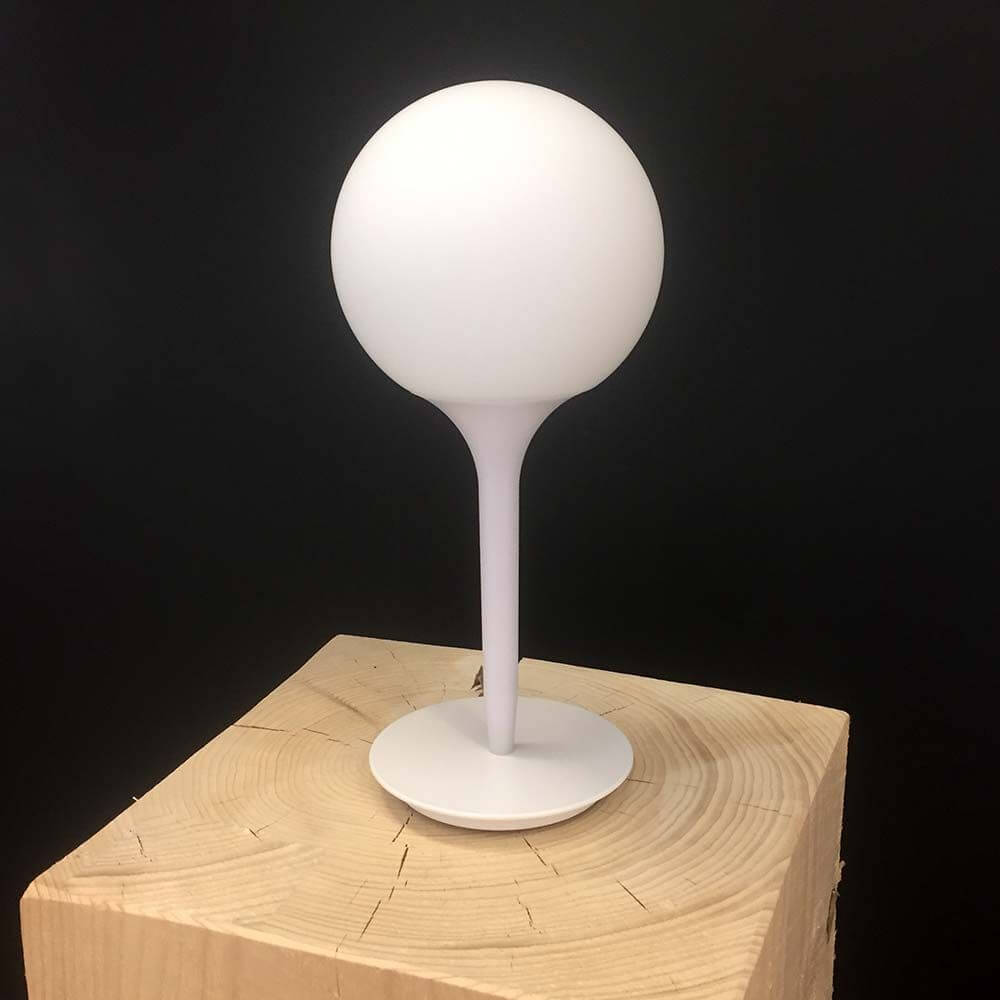 Artemide Castore Glas Tischleuchte mit rundem Schirm und minimalistischem Fuß auf Holzunterlage