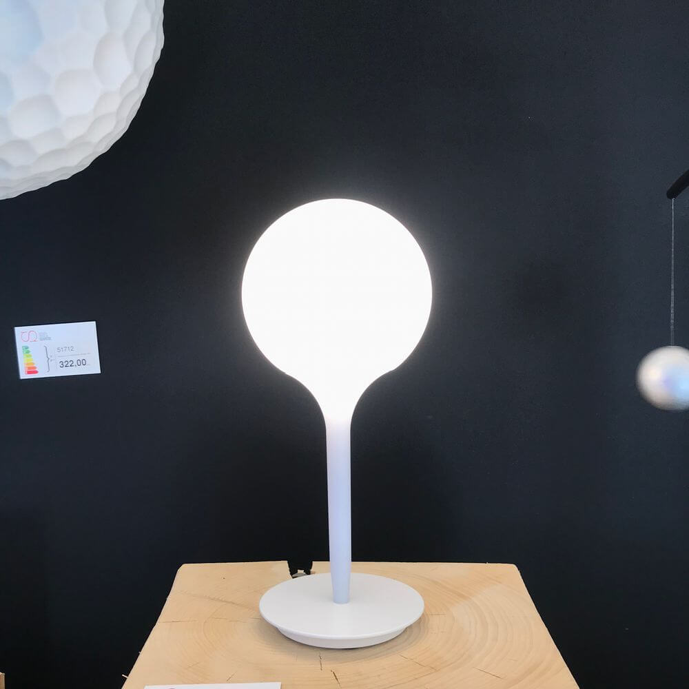 Artemide Castore Glas Tischleuchte in Weiß auf einem Holztisch, perfektes Design für Wohnräume.