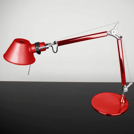 Artemide Tolomeo Micro Tischlampe in Rot mit elegantem Design und verstellbarem Arm, auf einem Tisch platziert.