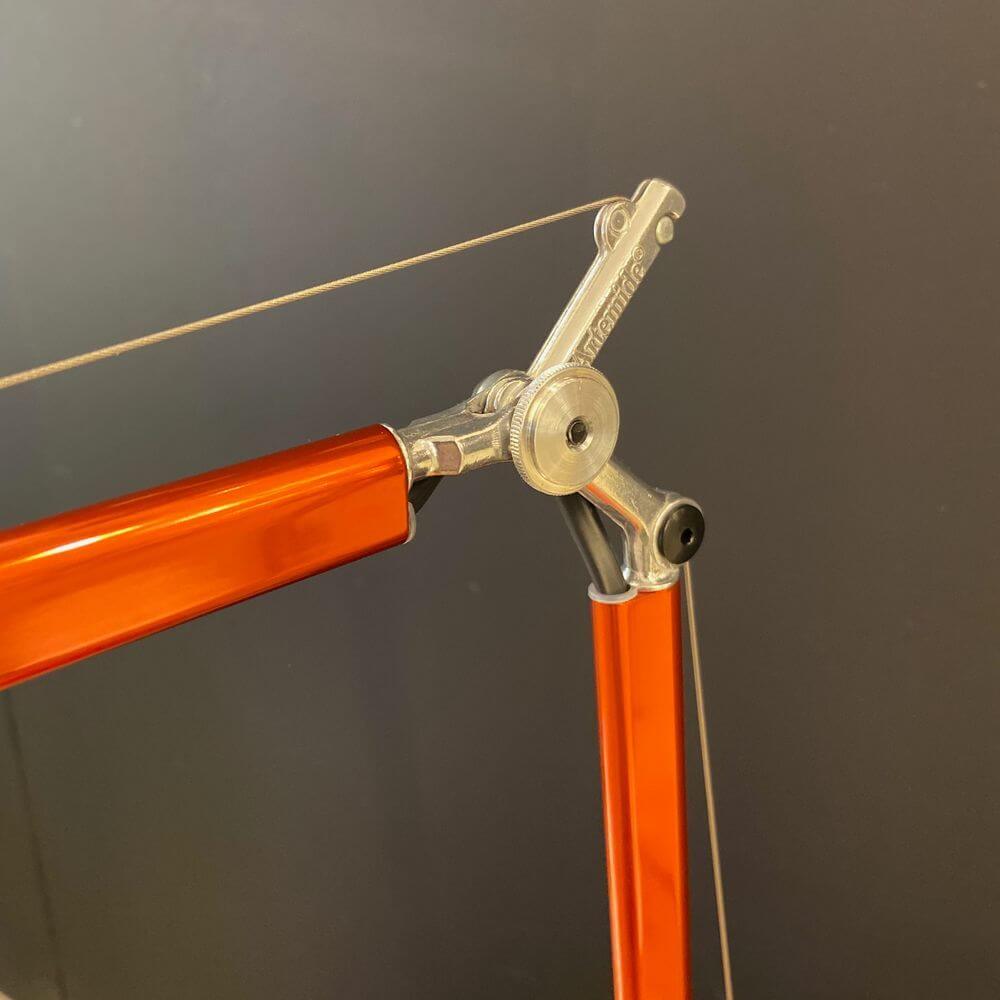 Detailansicht der Artemide Tolomeo Micro Tischlampe mit orangefarbenen Stangen und mechanischem Gelenk.