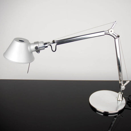 Artemide Tolomeo Micro Tischlampe in silberner Ausführung auf schwarzem Tisch mit elegantem Design.