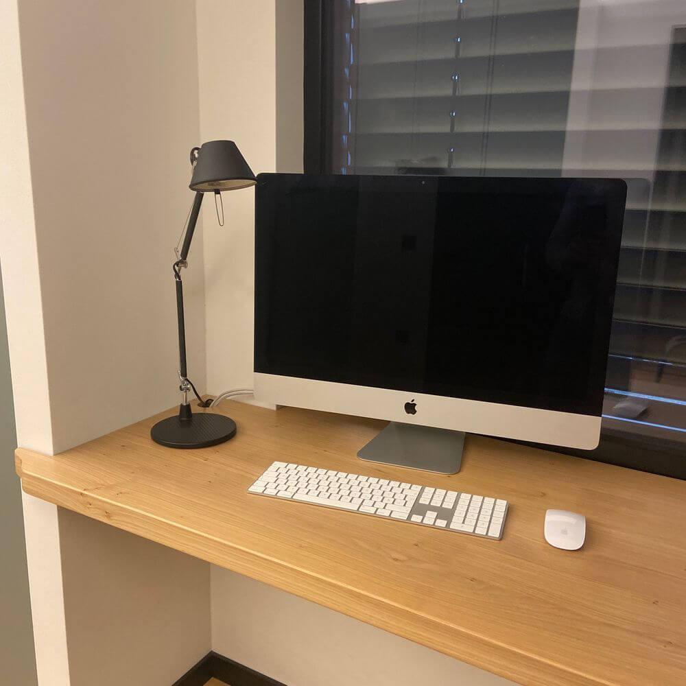 Artemide Tolomeo Micro Tischlampe neben einem iMac auf einem Holzschreibtisch, minimalistische Arbeitsplatzgestaltung.