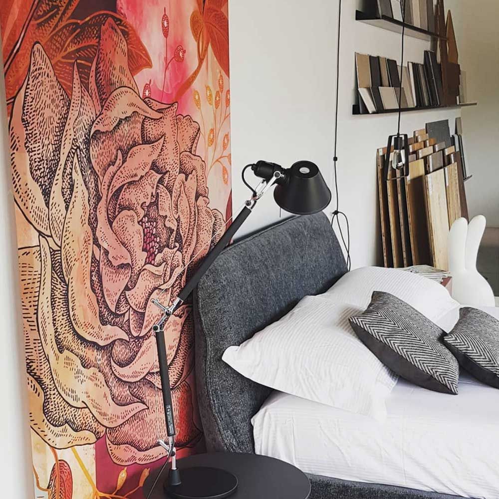 Artemide Tolomeo Micro Tischlampe neben einem gemütlichen Bett mit einer dekorativen Wandgestaltung.
