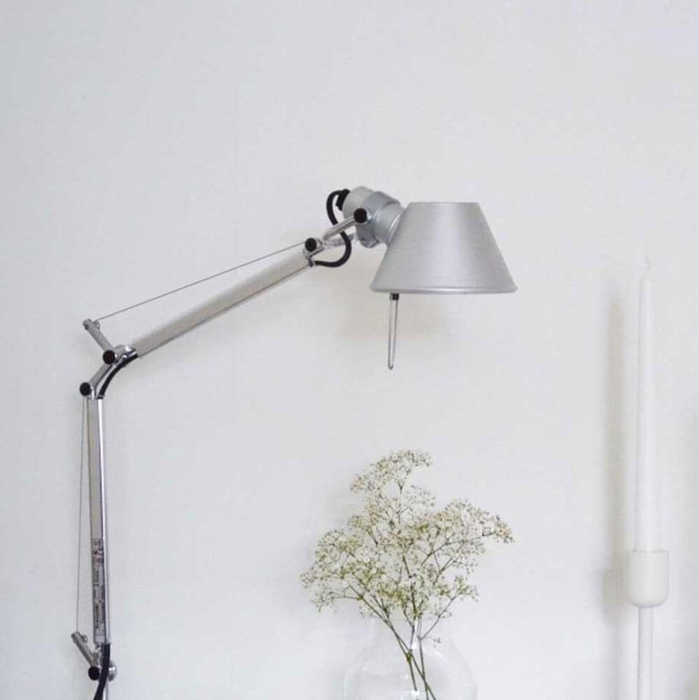 Artemide Tolomeo Micro Wandleuchte schwenkbar an einer Wand mit Dekoration und Kerze.