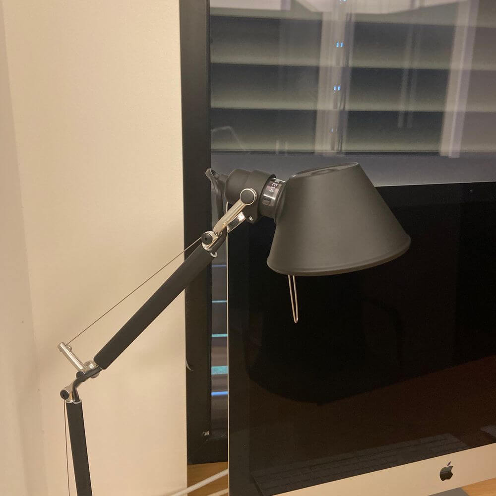 Artemide Tolomeo Micro Wandleuchte schwenkbar an einem Computer-Monitor angebracht.