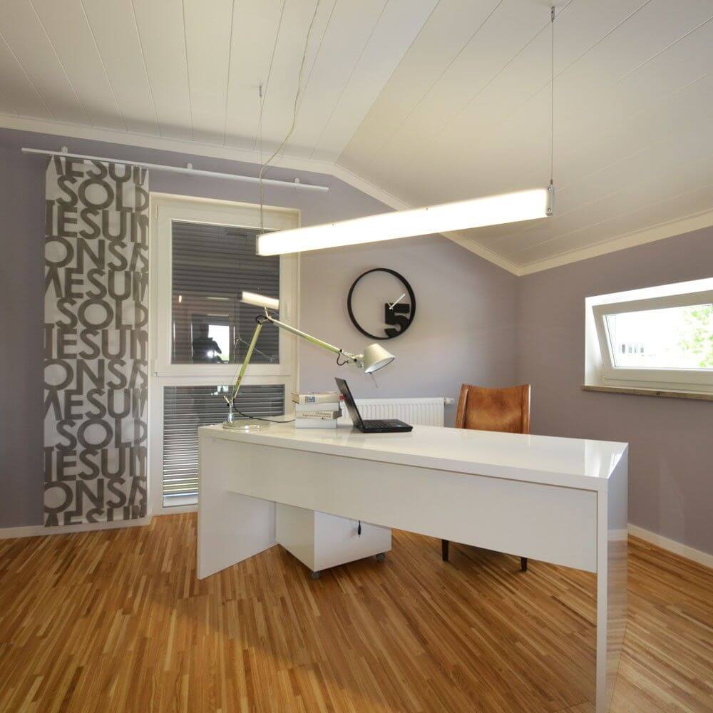 Modernes Büro mit weißem Schreibtisch, Schreibtischlampe und eleganter Wanddekoration.