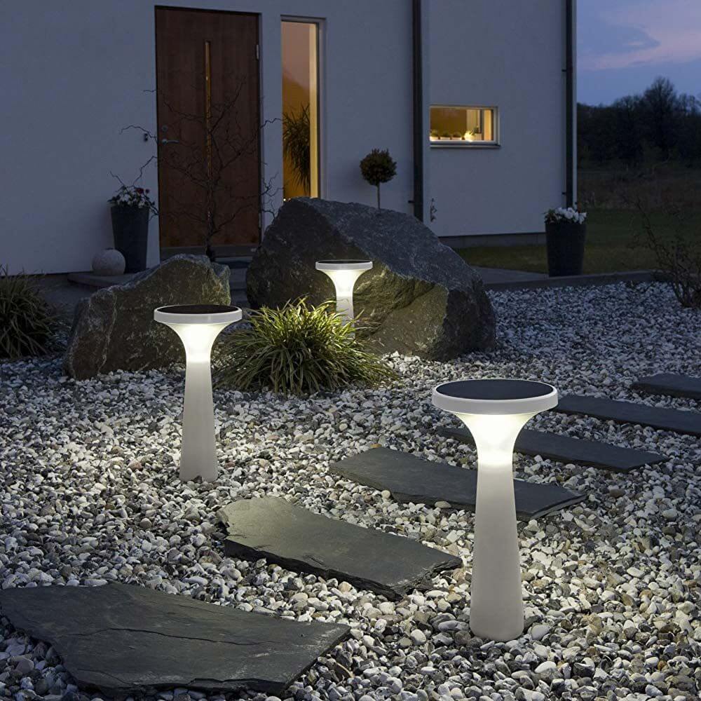 Solar LED Dekoleuchte Assisi Aton im Garten bei Nacht, beleuchtet Wege und Pflanzbereiche.