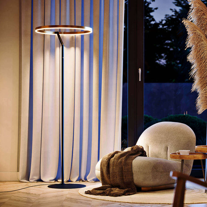 Moderne Stehlampe mit runder Leuchte in stilvollem Wohnzimmer, umgeben von Vorhängen und gemütlichem Sessel.
