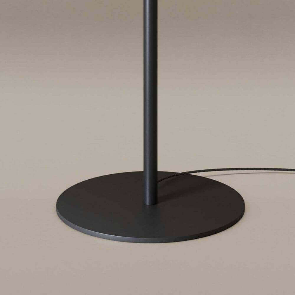Moderne Stehlampe mit schwarzem Standfuß und Kabel, elegantes Design für stilvolle Innenräume.