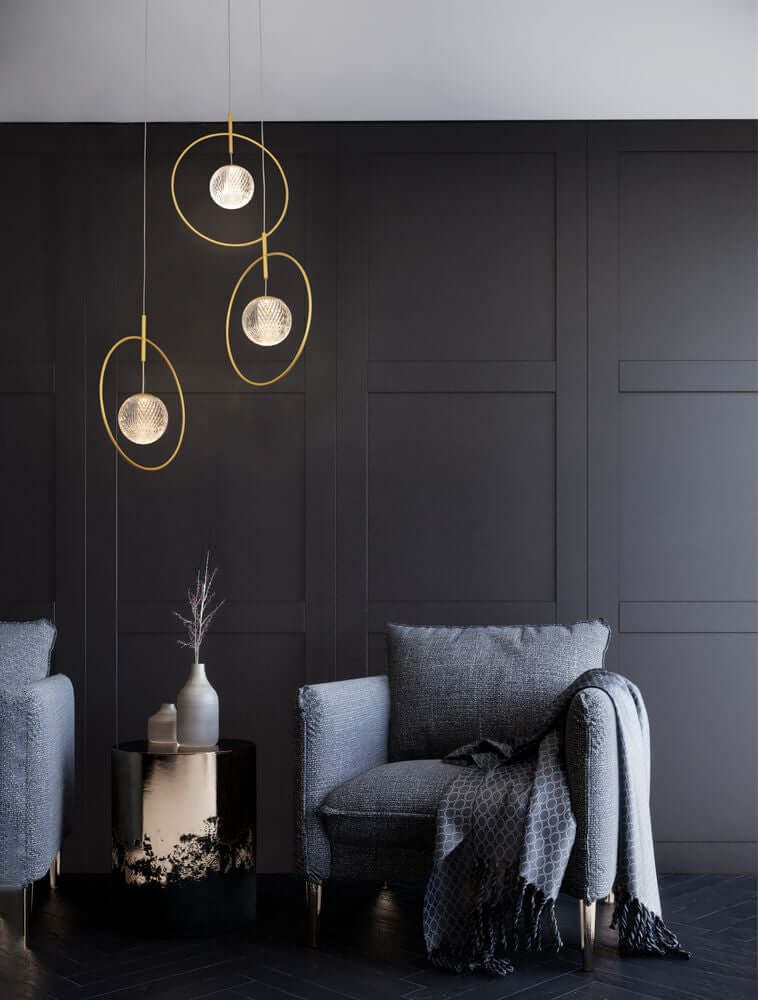 Atos LED Pendelleuchte Ø 40cm 3-flammig Gold 3000K in modernem Wohnambiente mit gemütlichem Sessel.