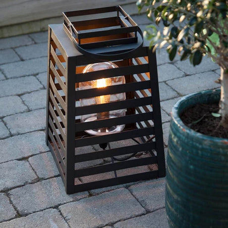 Yankton outdoor floor light IP44 sand black on the terrace with plants and stone flooring.