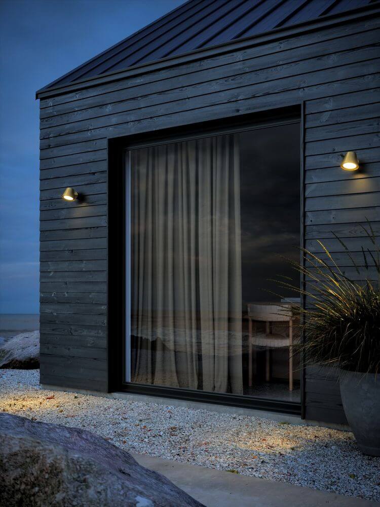 Außenwandlampe Aleria IP44 an einem modernen Holzhaus, das eine einladende Atmosphäre im Außenbereich schafft.
