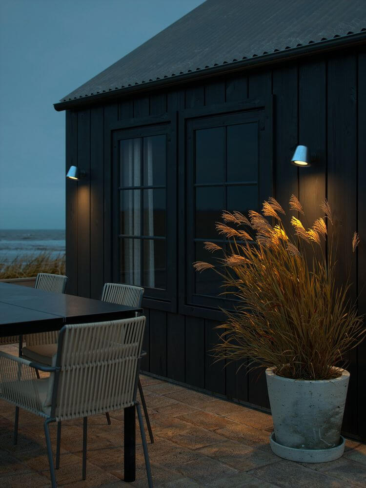 Außenwandlampe Aleria IP44 an einem modernen schwarz gestrichenen Haus im Außenbereich.