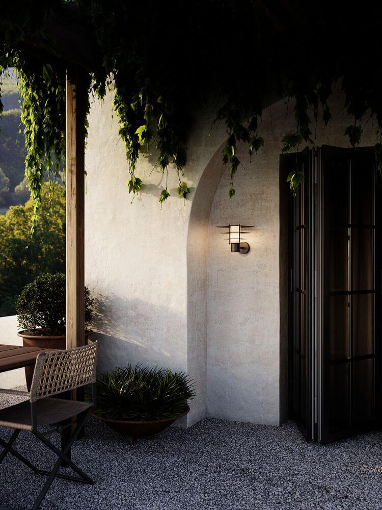 Außenwandlampe Bastia 35 IP54 an einer stilvollen Wand in einem Gartenbereich.