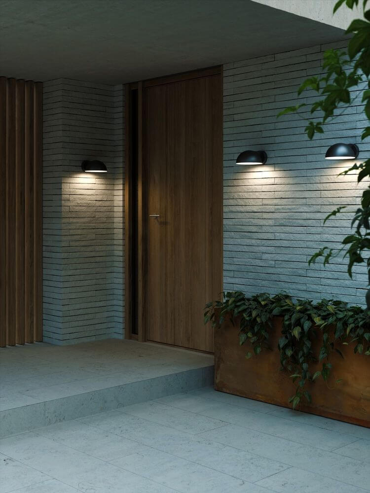 Außenwandlampe Clarso IP44 an der Wand neben einer Holzhaustür, strahlt sanftes Licht aus.