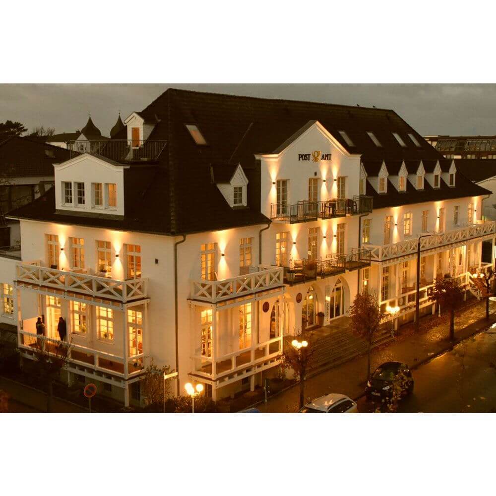 Außenansicht des Hotels mit warmen Lichtern bei Nacht, moderne Architektur und einladende Atmosphäre.