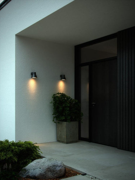 Außenwandlampe Kyklop Cone IP54 beleuchtet einen Eingangsbereich mit dekorativem Licht.