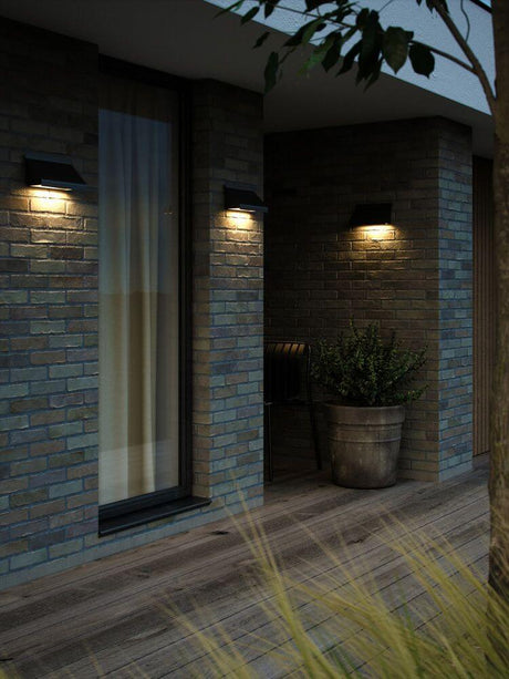 Außenwandlampe Tadas IP54 an moderner Backsteinfassade mit nach unten gerichtetem Licht