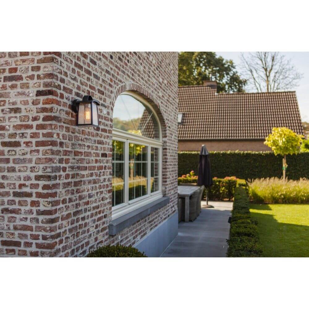 Außenwandleuchte Kelsey IP44 Schwarz an einer Backsteinwand mit Fenster und Gartenlandschaft.