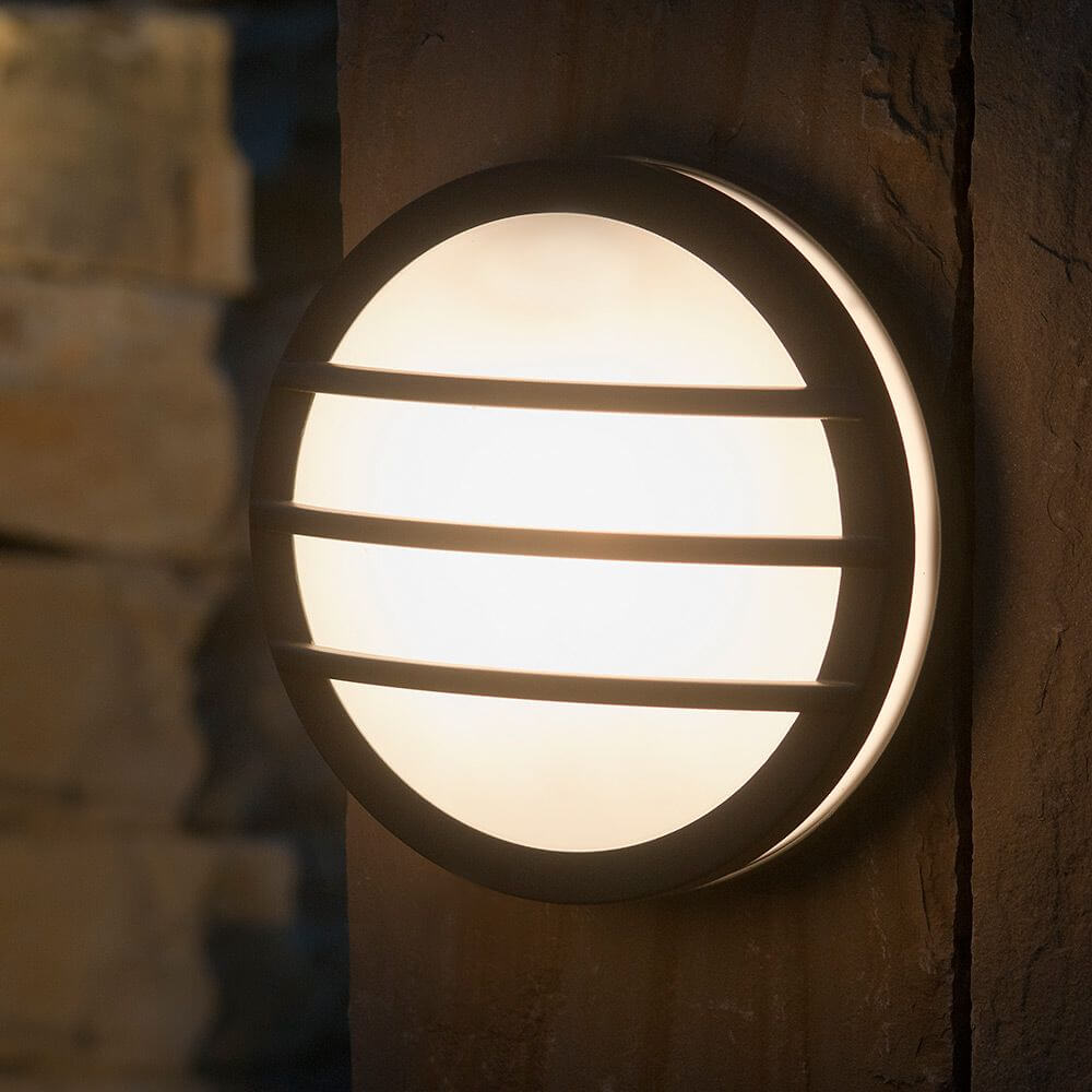 Außenwandleuchte Seine IP54 Anthrazit an einer Wand montiert, runde, flache Form mit diffundierendem Licht.