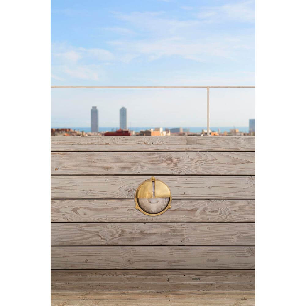 Außenwandleuchte TIMON IP44 Messing maritim an einer Holzwand mit Meerblick im Hintergrund