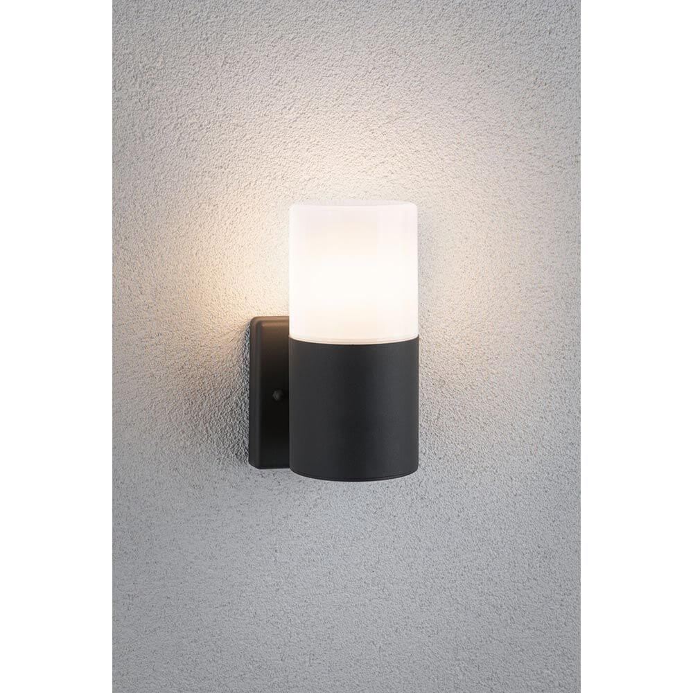 Außenwandleuchte Tubs Rund Grau-Matt Metall an einer Wand installiert, strahlt sanftes Licht aus.