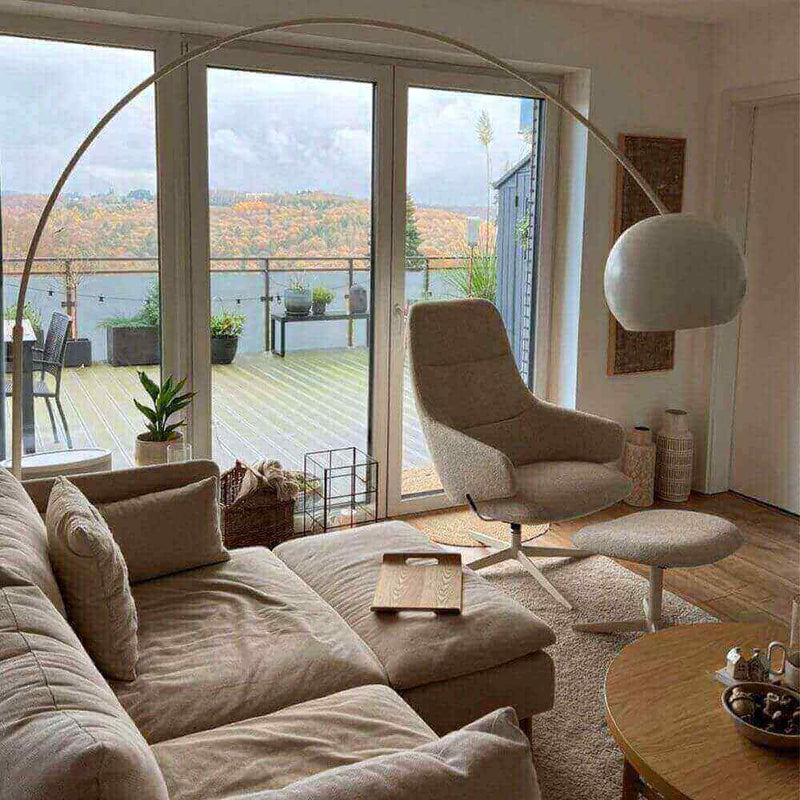 Modernes Wohnzimmer mit bequemer Couch, Stehlampe und Blick auf die Terrasse im Herbst.