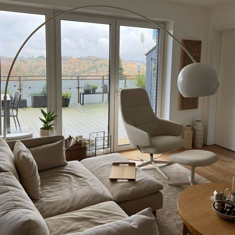 Modernes Wohnzimmer mit bequemer Couch, Stehlampe und Blick auf die Terrasse im Herbst.