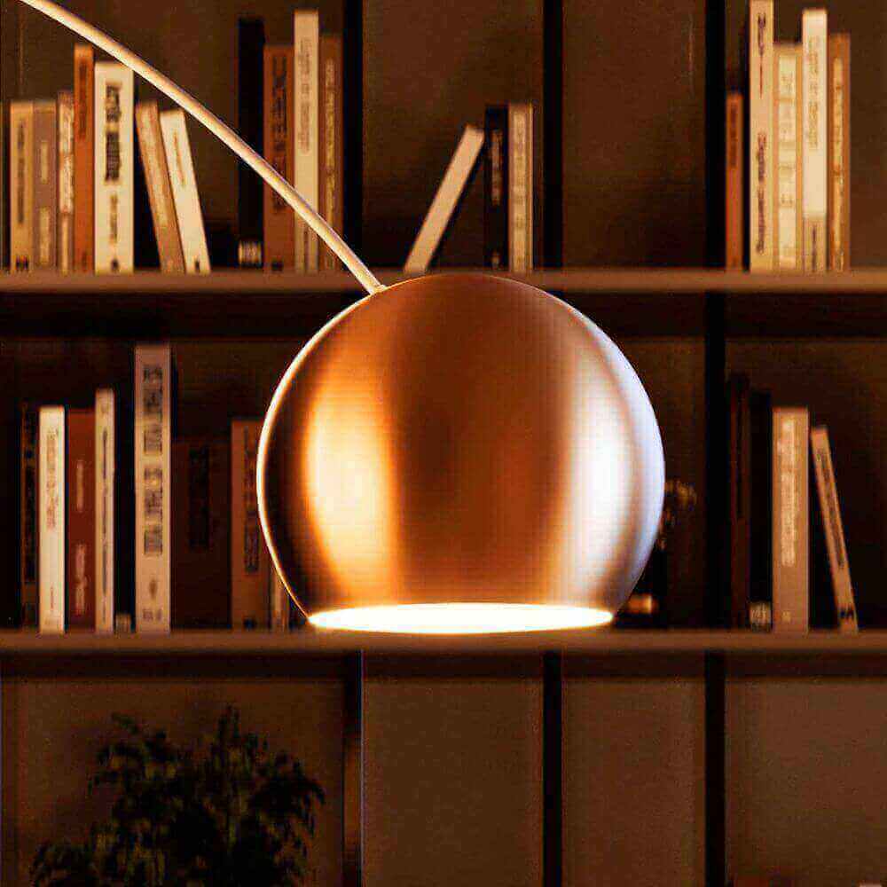 s.luce Lampe arc de design Ball avec pied en marbre moderne au-dessus d'une bibliothèque éclaire la pièce.